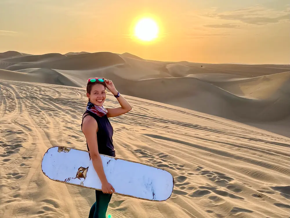 The blog's author standing in a desert holding a sand board.