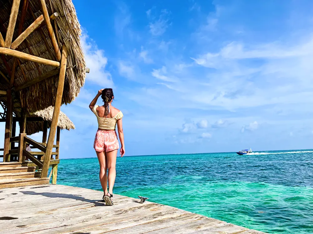 The blog author looking out at Belize's blue ocean while on a swimming dock.