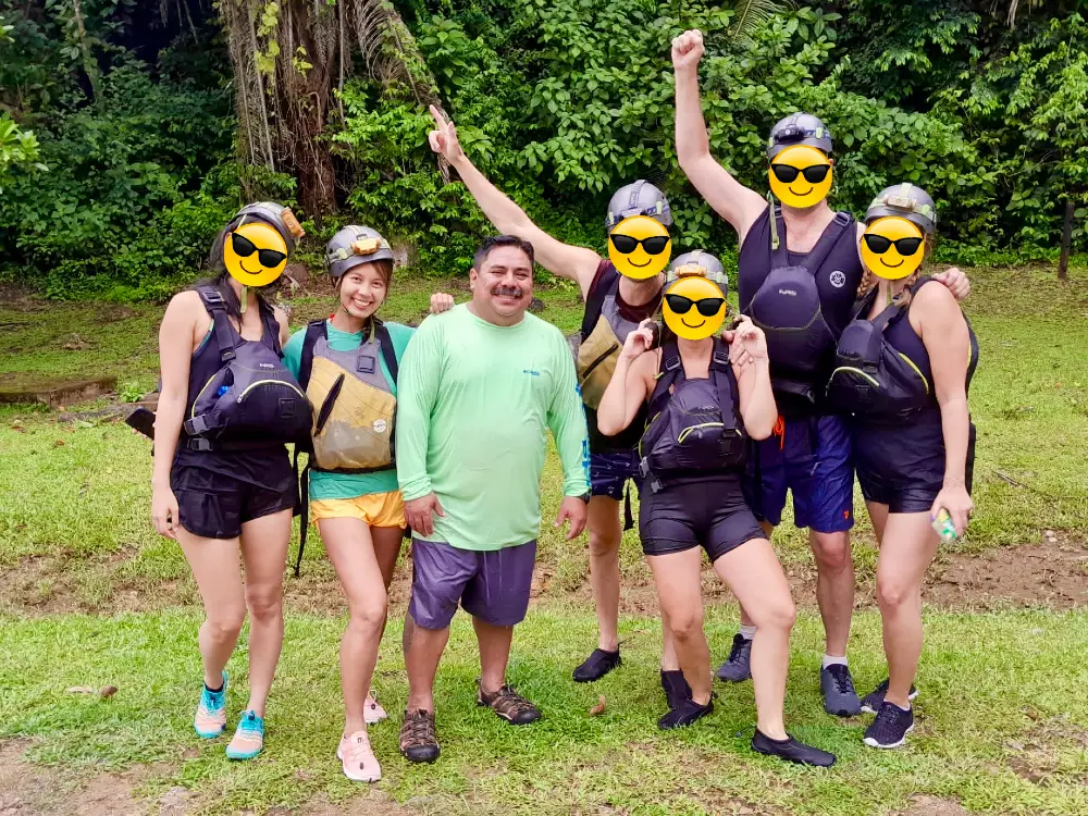 A group of 6 people with a guide wearing helmets, shorts and life jackets.