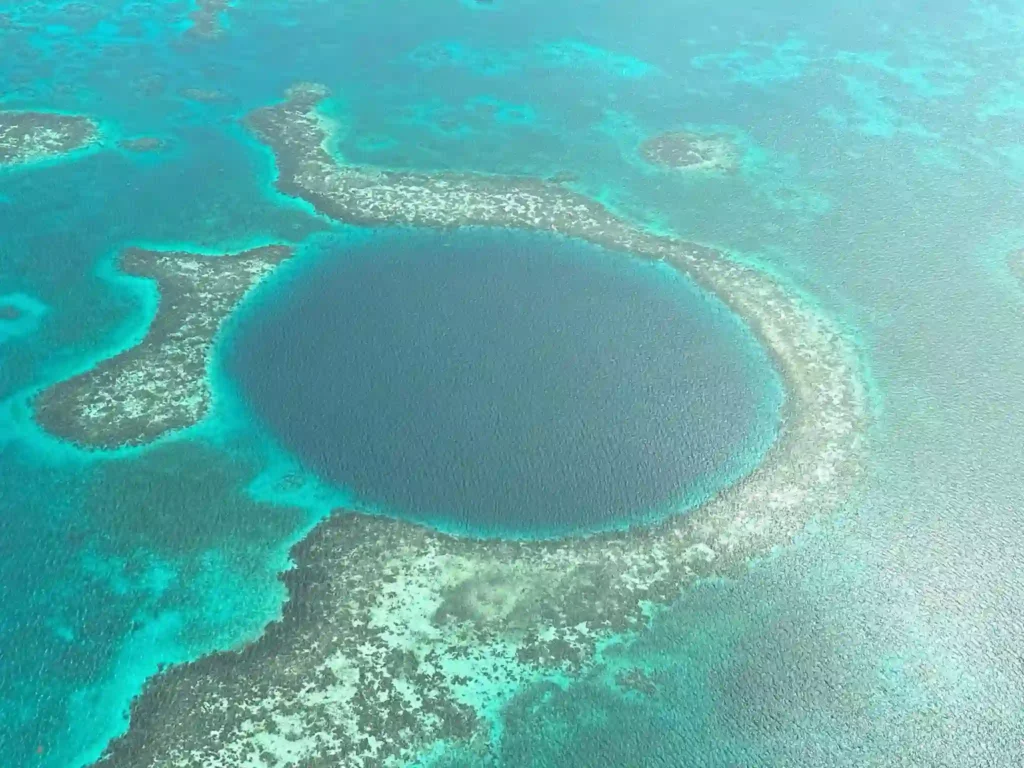 A view of a big, blue sinkhole in the ocean, taken from sky high.