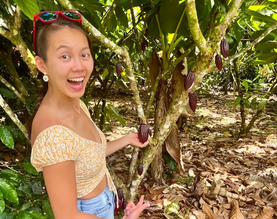 A woman holding and pointing at a cocoa bean.
