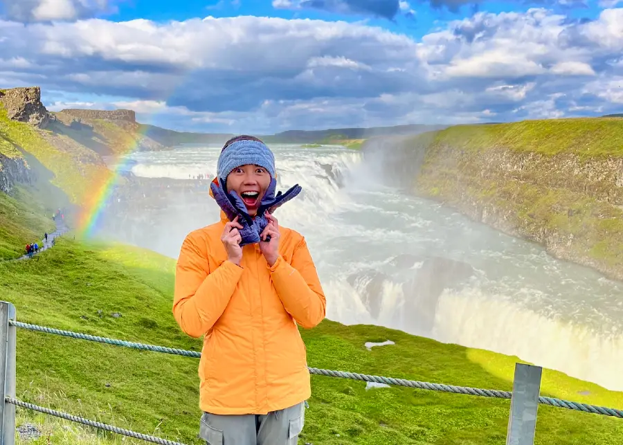 The blog author with a happy expression with a giant rainbow and waterfall in the background.