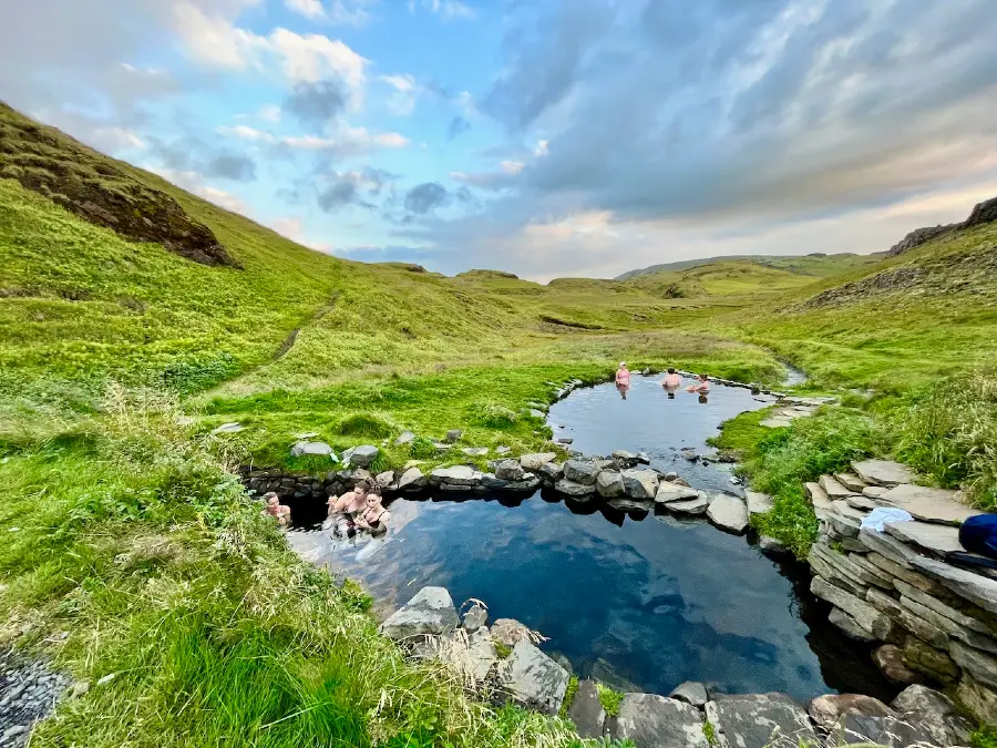 Two hot springs in a green valley and open sky.