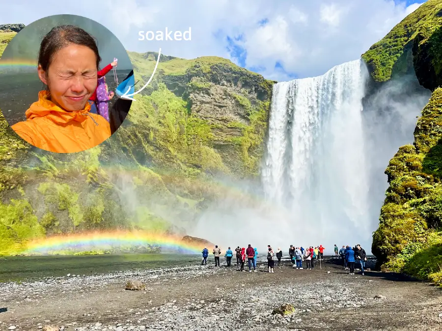 A giant waterfall with two rainbows at its based. A selfie of a woman with her eyes closed from getting wet.