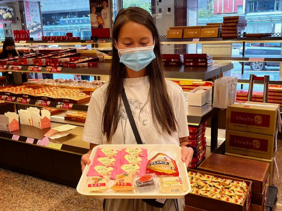 Blog author holding a tray with packaged pastries organized on it.