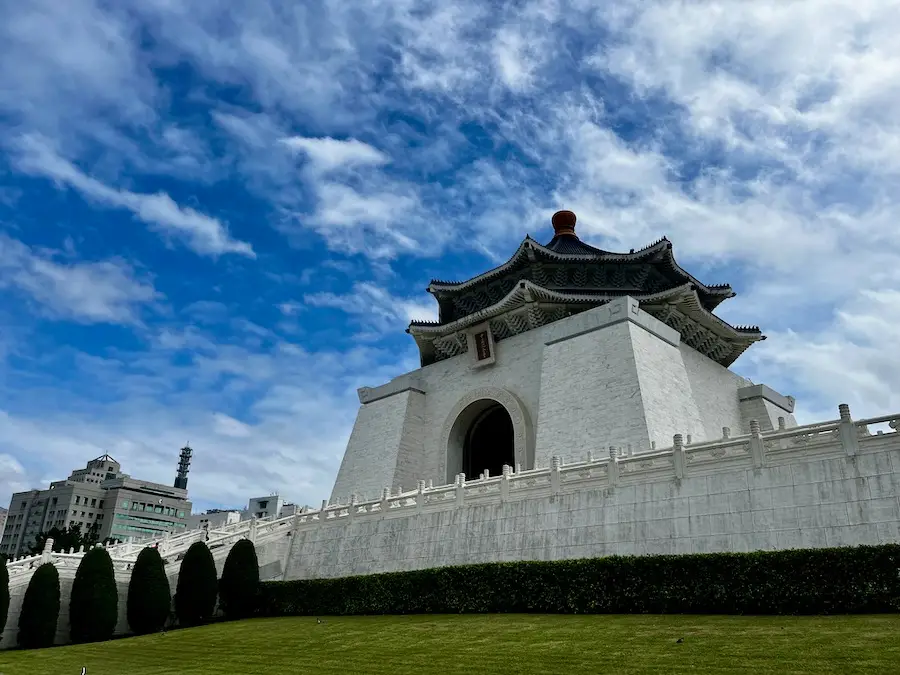 A white building with a decorative top and archway on green grass.