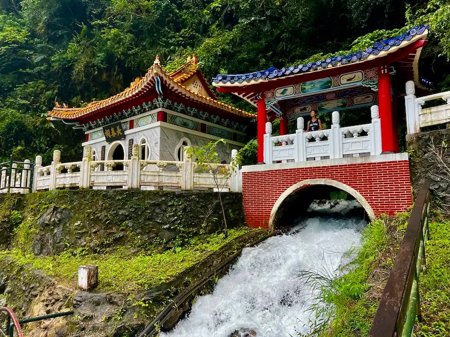 A woman on an Asian-style shrine with red bricks on a waterfall.