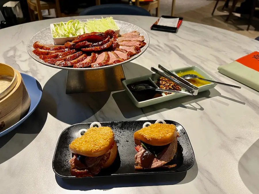 Peking duck served on a plate with two cartoon-bread with peking duck as tongues.