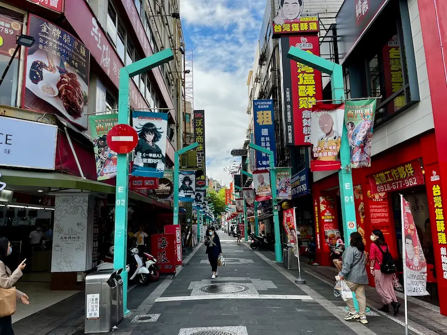 A street with Chinese signs and anime-decorated posters.