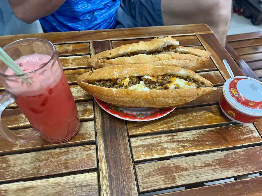A baquette stuffed with egg and pork with watermelon juice on the side.
