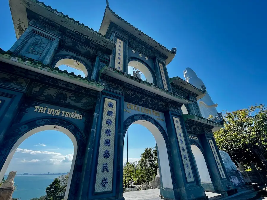 Gates with decorated archways and a giant statue in the background.