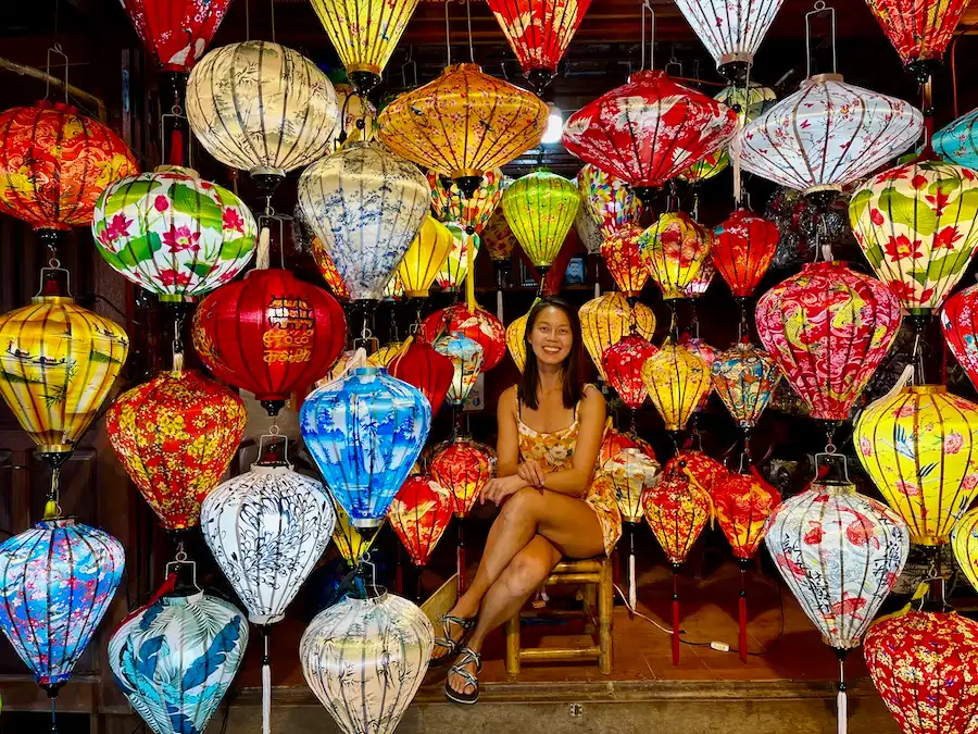 The blog author sitting down while being surrounded by more than a dozen lanterns.