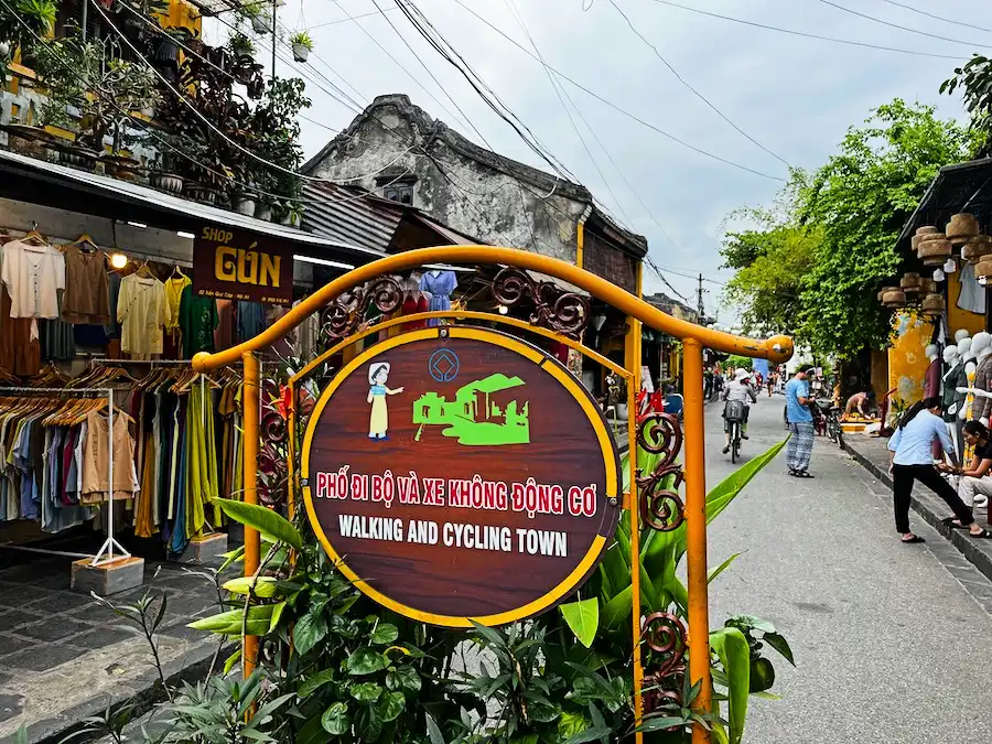 A sign on a street that says "Walking and Cycling Town" in English and Vietnamese.