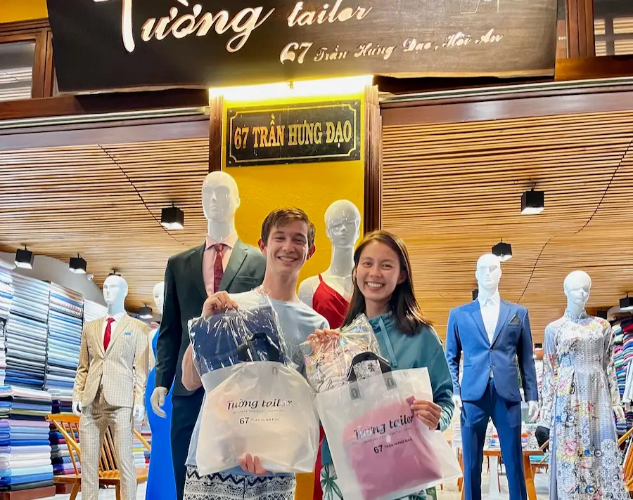 Two people holding a bag with packaged clothes inside.