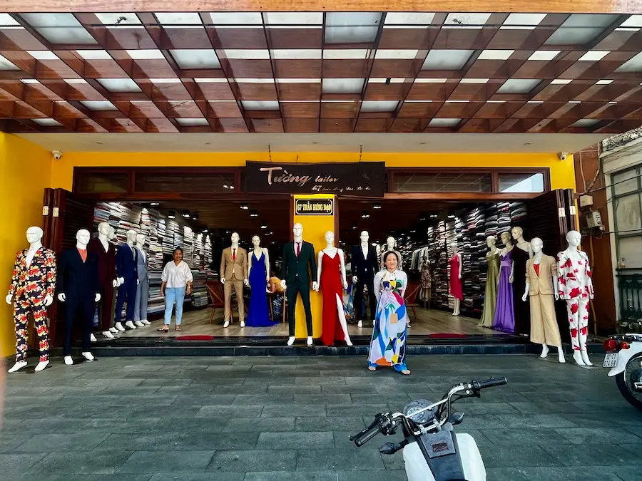 A shop with many mannequins wearing suits and dresses at the entrance.