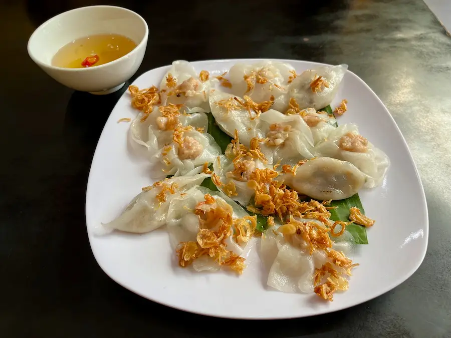 Shrimp and vegetable dumplings with golden shallots on a plate.
