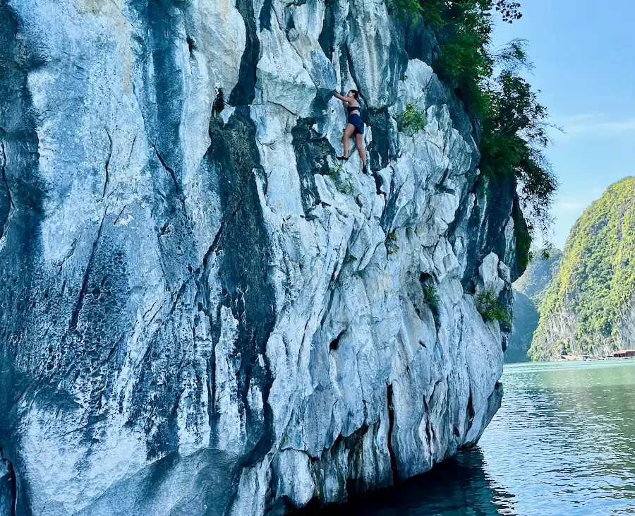 The blog's author climbing up a gray limestone rock over water.