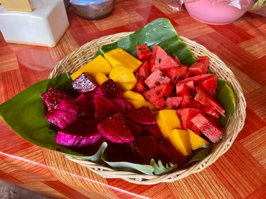 A weaved basket holding dragonfruit, mango and watermelon.