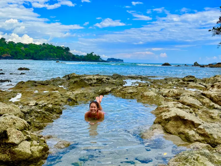The blog author laying down inside a tide pool part of an ocean surrounded by jungle.