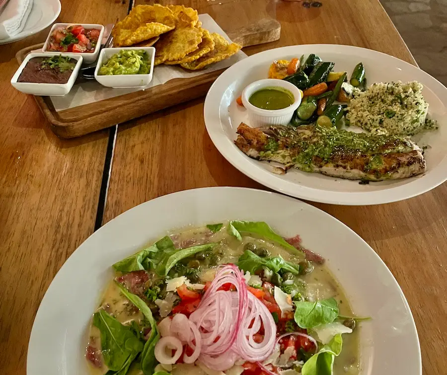 A plate of salad, fish and tostones with dips.