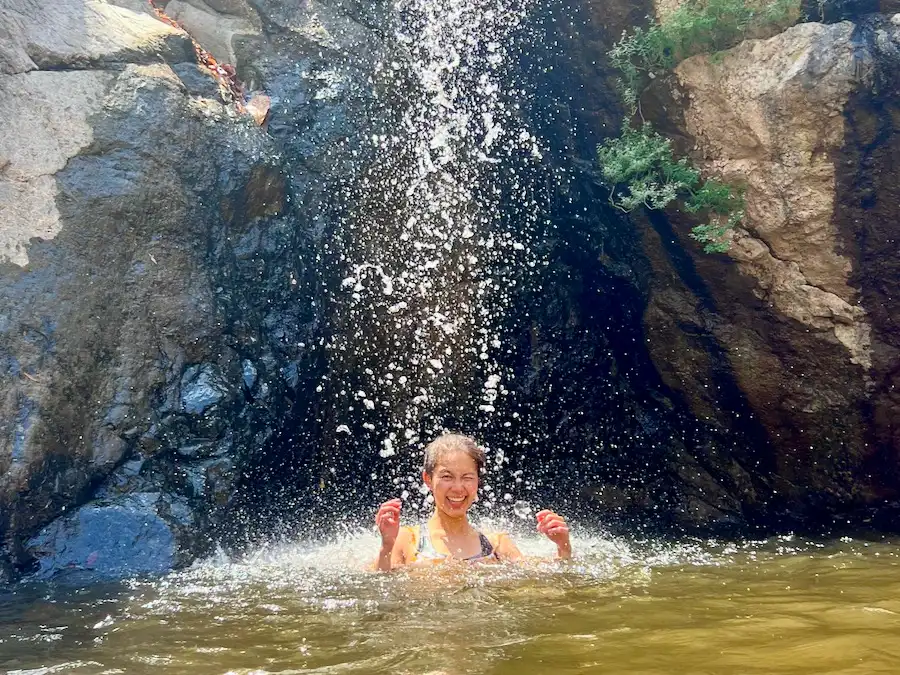 The blog author smiling while playing under a waterfall.