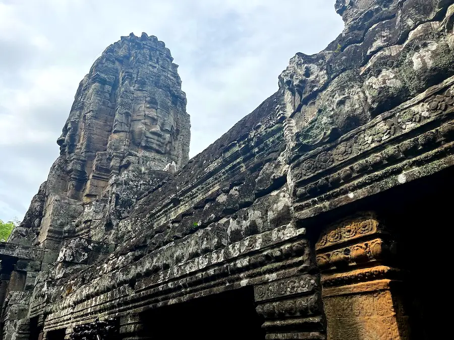 A Cambodian ruin with the face of a smiling Buddha carved into it.