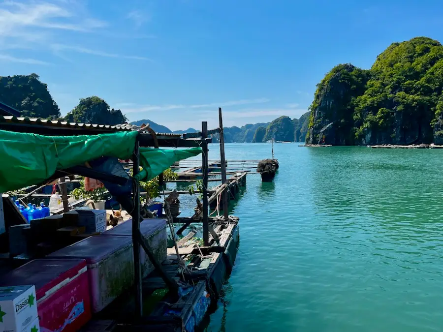 A wooden makeshift boat market floating in emerald-green water.