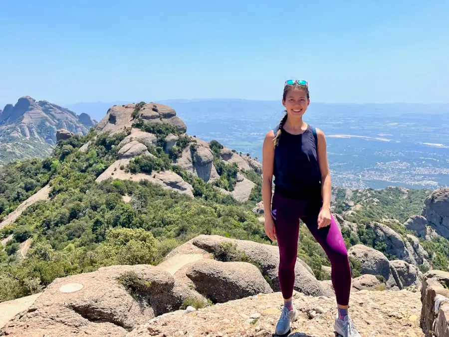 The blog author standing on a mountain with sky blue views in the horizon.