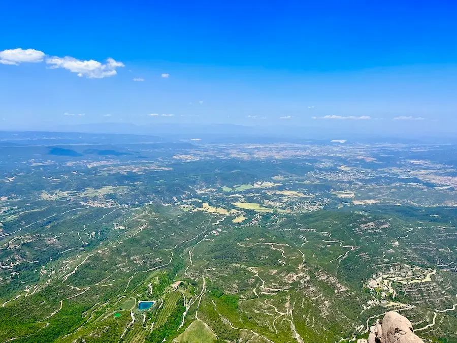 A high view looking down at green land and an open, blue sky.