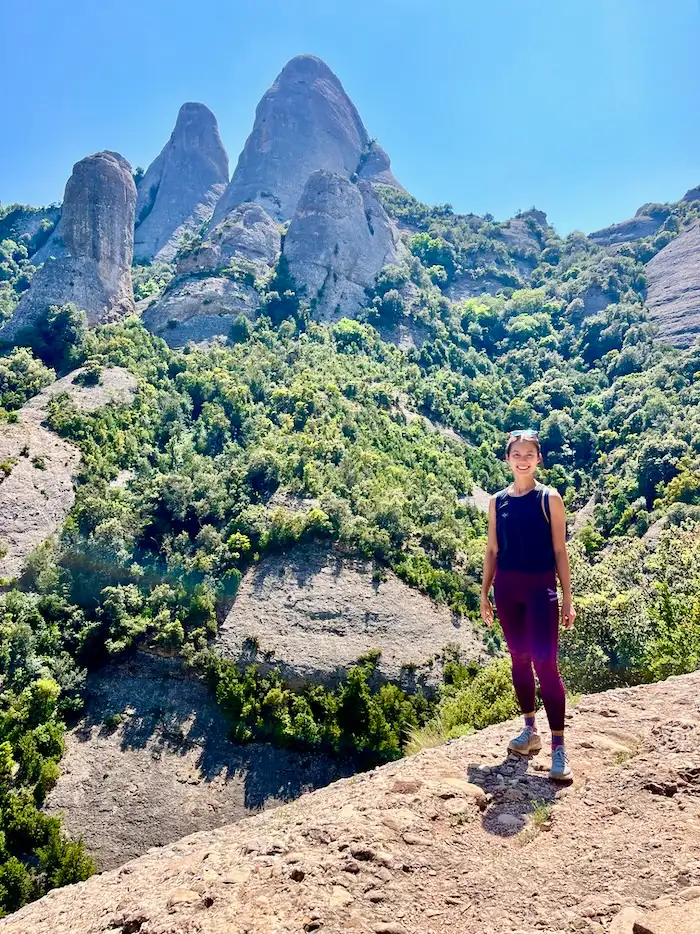 The blog author standing at the edge of a mountain with mountain peaks in the background.