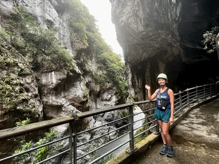 The blog author with a hard helmet in front of marble mountains with trees.
