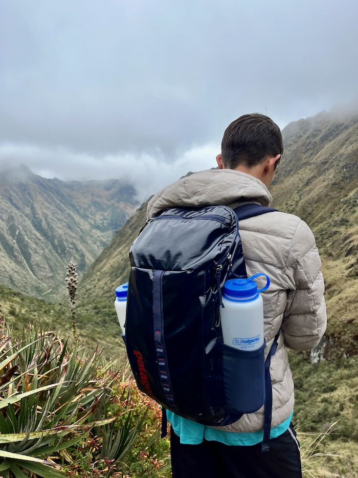 A hiker carrying a 25L daypack with two water bottles.