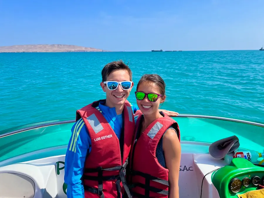 Two people wearing life jackets and sunglasses on a boat.