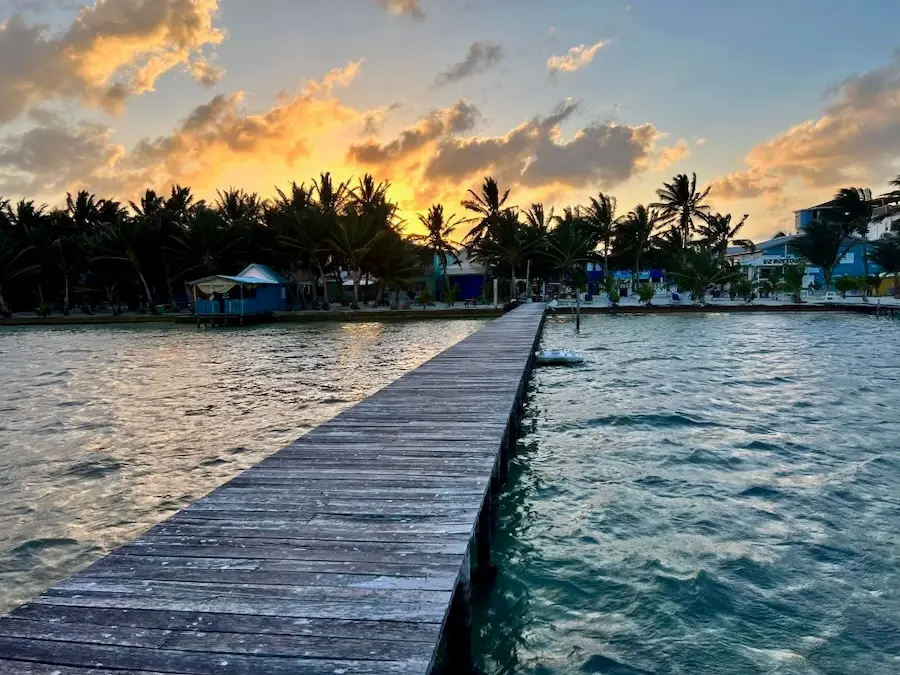 A swimming dock path stretching across an ocean during sunset.