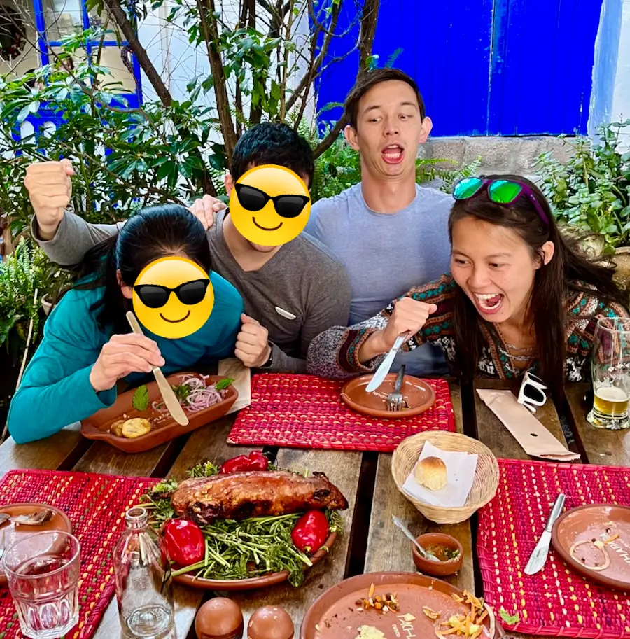 Four people about to eat a dish holding a whole roasted guinea pig.