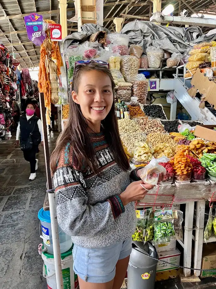 Woman standing in front of a dry fruit market stand.