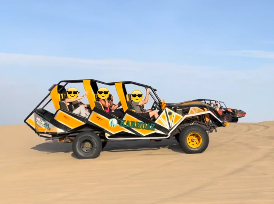 A few people riding an open vehicle over sand.