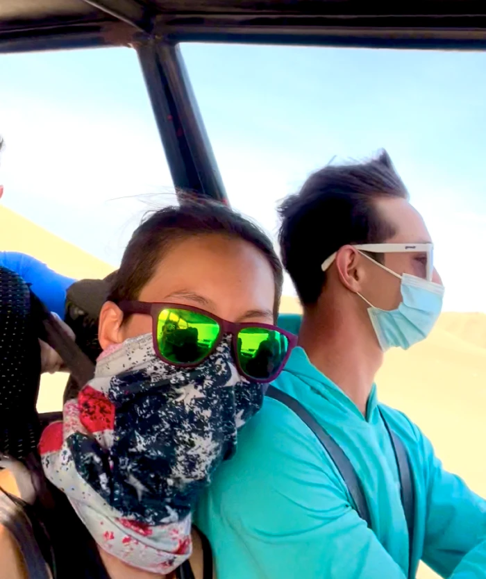 Two people in an open vehicle wearing masks and a buff.