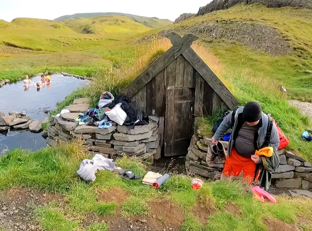 A small hut in a valley with many people's possessions around it.