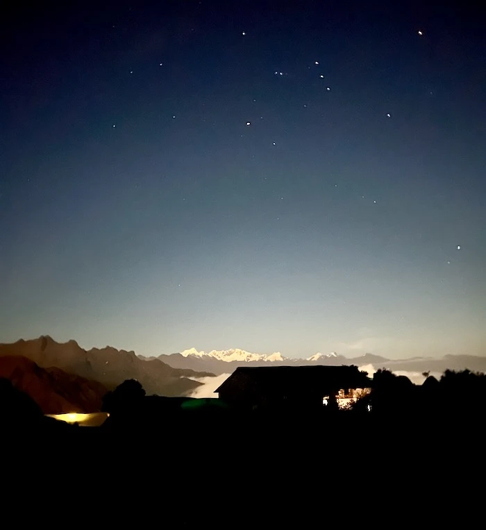 An open sky with stars over a campsite on a mountain.