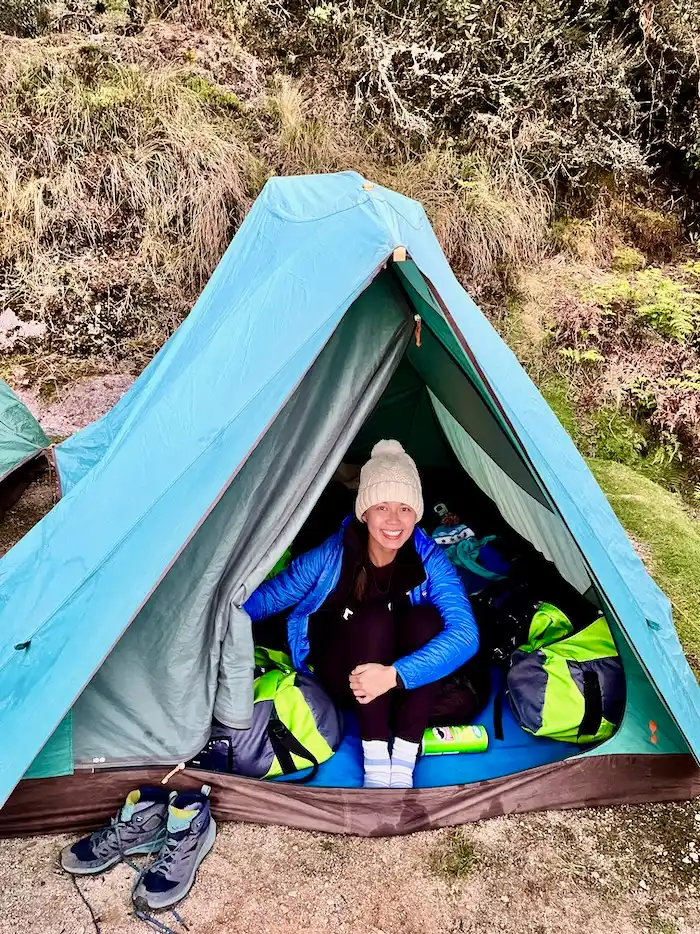 A woman with warm layers sitting inside a tent.