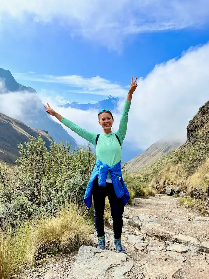 A woman hiker posing in front of a stunning mountain view.