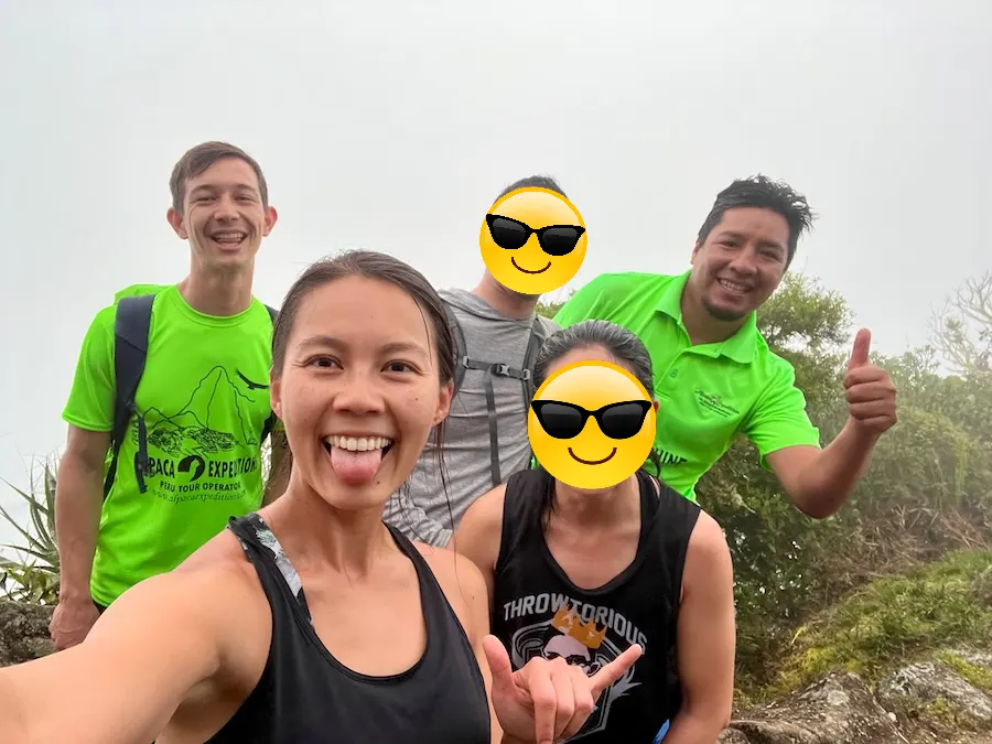 A selfie of five people standing on a mountain with white fog in the background blocking the view.