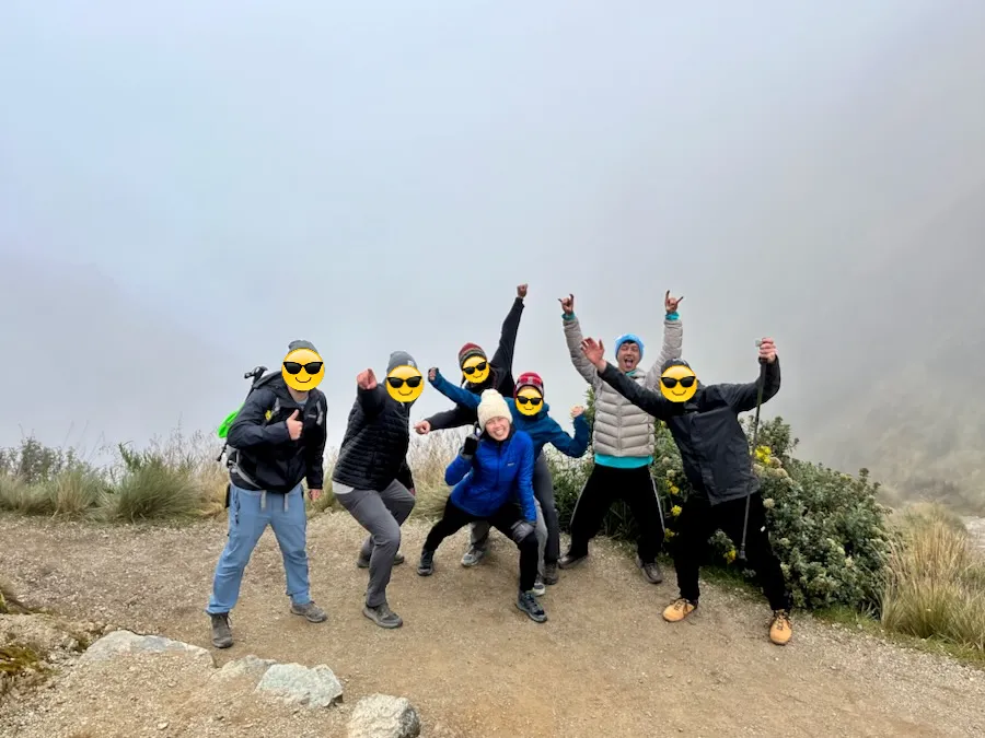 A group of people posing on a mountain with a foggy view behind them.