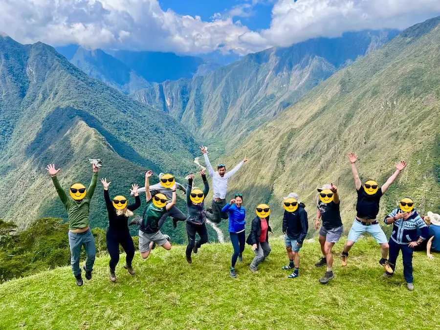 A group of hikers jumping for a photo against a scenic mountain background.