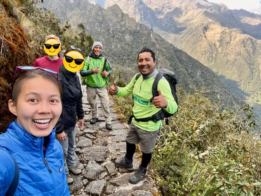 A group of people posing for a selfie while on a mountain trail.
