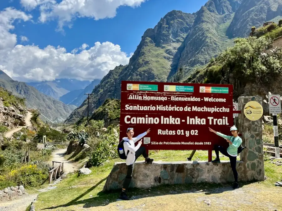 Two hikers pointing at a sign that says Welcome and Inca Trail.