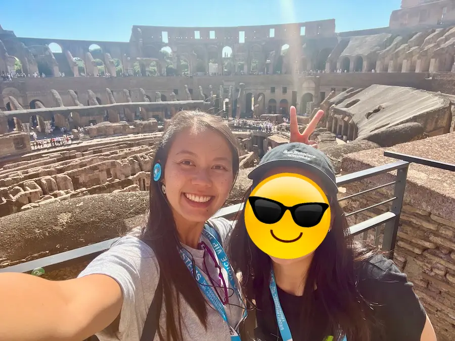 Two women posing for a selfie in front of an ancient ampiteather. 