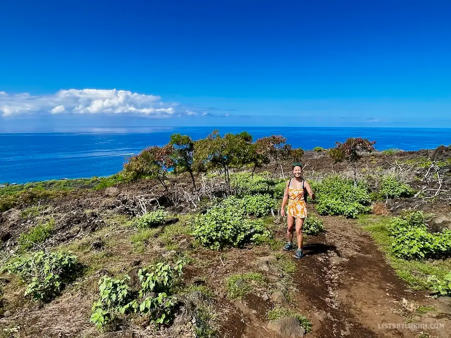A woman hiking on a dirt road overlooking the ocean.