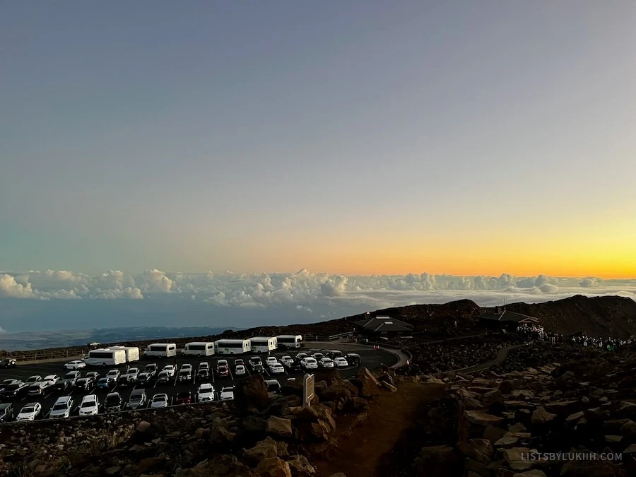 A parking lot full with vehicles, on top of a mountain.